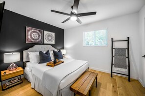 A bedroom with a bed, bedside tables, a ceiling fan, artwork, a window, and a bench. - Peaceful Sola Hideaway w Private Patio (Austin)