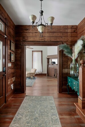 A wooden interior with a chandelier, a blue rug, and a teal dresser. - Charming 5 Bedroom Home in Austin (Austin)