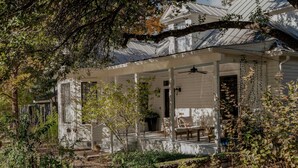 A white house with a porch, a covered entryway, and a small garden area. - Charming 5 Bedroom Home in Austin (Austin)