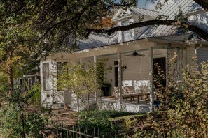 A white house with a porch, a covered entryway, and a small garden area. - Charming 5 Bedroom Home in Austin (Austin)