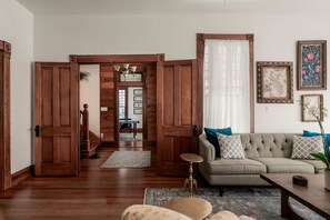 A living room with a sofa, a coffee table, a rug, and wooden doors. - Charming 5 Bedroom Home in Austin (Austin)