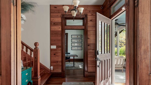 A wooden interior hallway with a staircase, a door leading outside, and a rug on the floor. - Charming 5 Bedroom Home in Austin (Austin)