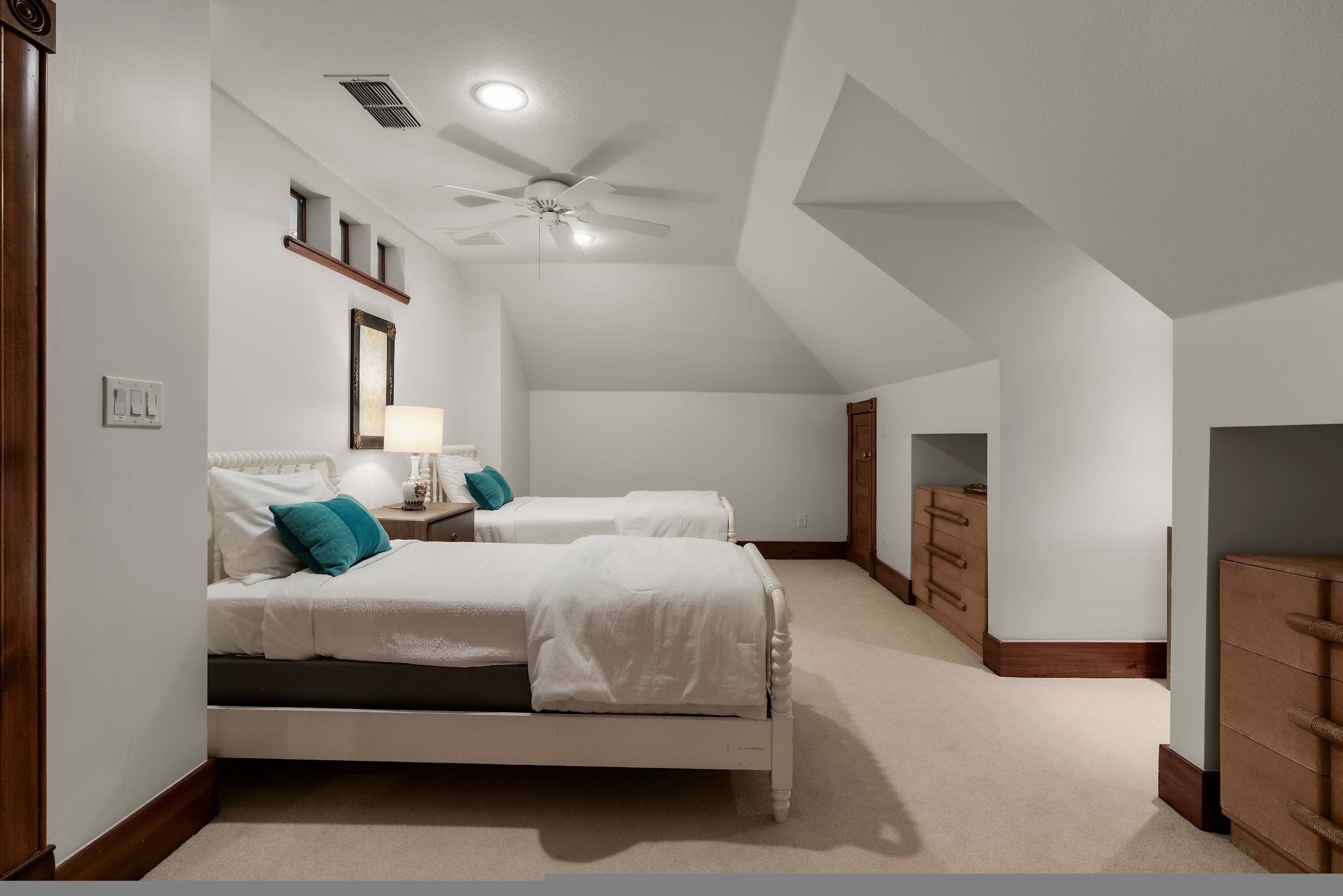 A bedroom with two beds, a ceiling fan, a nightstand, and a dresser.