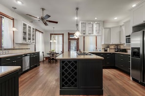 A modern kitchen with dark cabinetry, a central island, and a ceiling fan. - Charming 5 Bedroom Home in Austin (Austin)