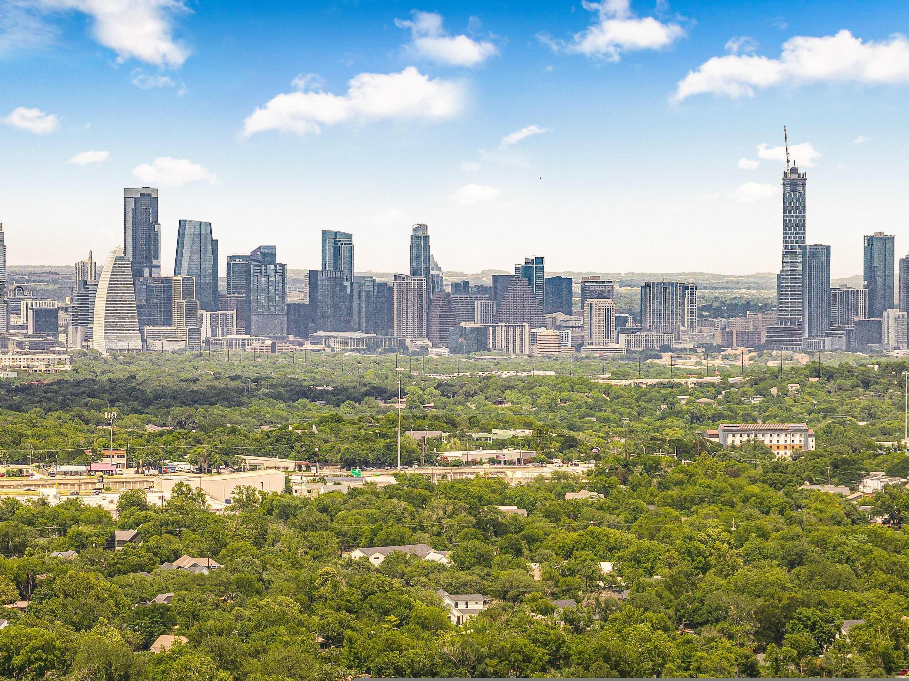 Horizont einer Stadt mit modernen Hochhäusern und einer grünen Fläche im Vordergrund.