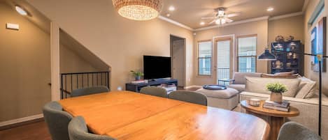 A dining area with a wooden table and chairs, a ceiling fan, and a television in the background.