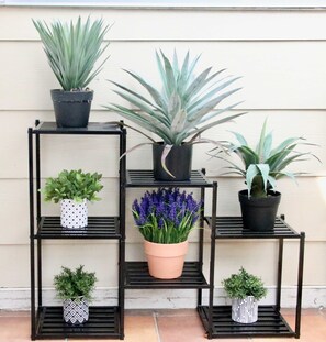 A black metal shelving unit with potted plants and flowers. - Modern 3BR Townhouse Near Zilker Park (Austin)