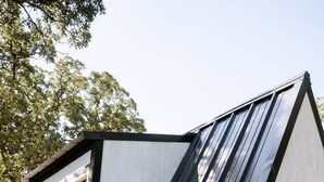 Un bâtiment moderne doté d’un toit en pente, d’une porte en bois et de fondations en béton.