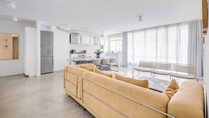 A modern living room with a sofa, a dining table, and a kitchen area in the background. - Modern 1bdr/2p Flat With a Balcony - Menilmontant (Paris)