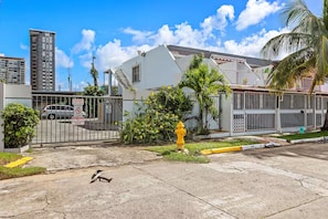 A gated residential area with a yellow fire hydrant, a white building, and a tall apartment building in the background. - Calm Cove Retreat a unique accommodation next to beautiful beaches Luquillo, PR. (Luquillo)
