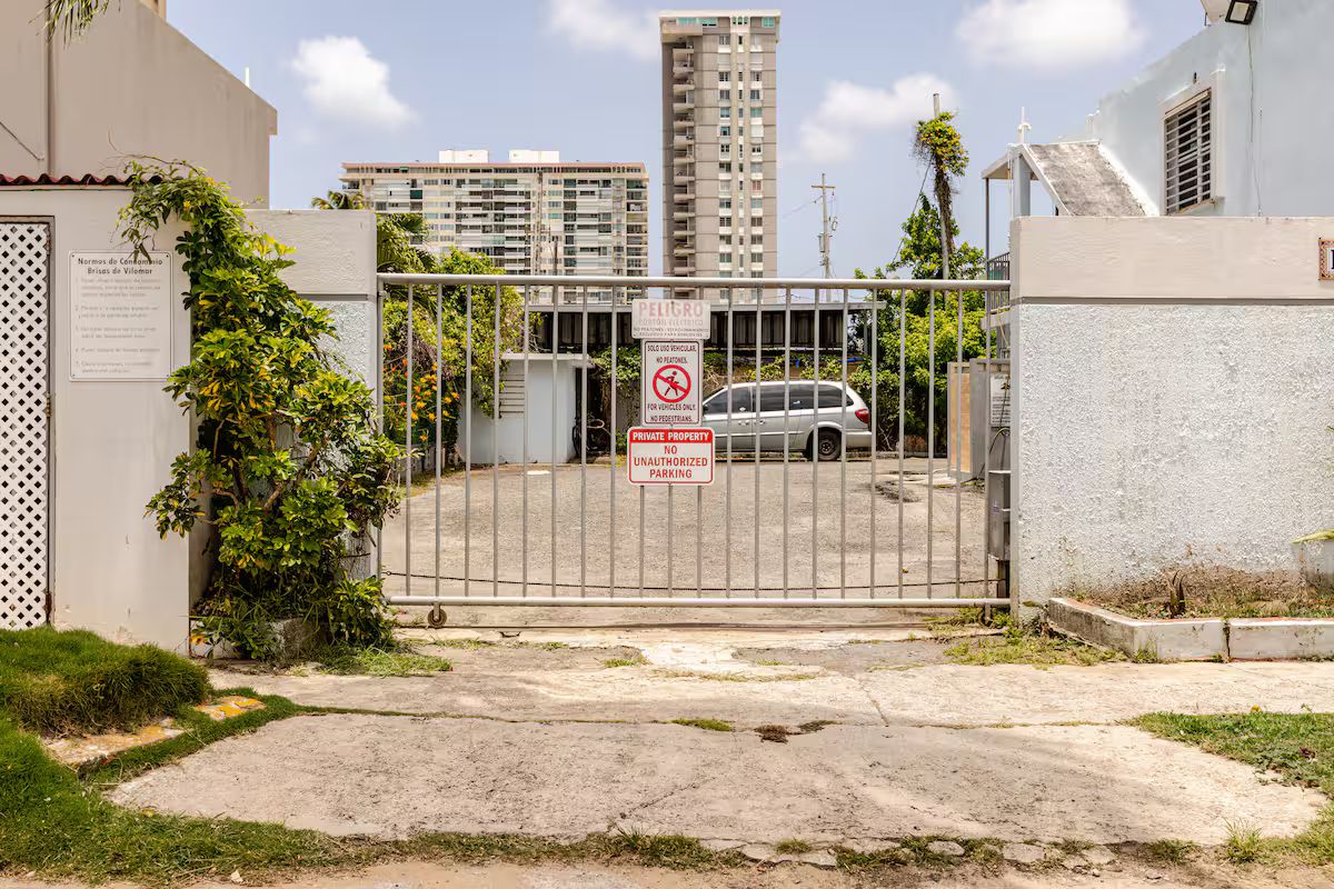 A gated entrance with a no unauthorized parking sign, a private property notice, and a building in the background.