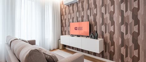 A modern living room with a sofa, a white console table, and a flat-screen TV displaying "GUEST READY".