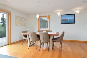 Uma sala de jantar com uma mesa de madeira, quatro cadeiras, um mapa na parede, uma janela e uma moldura com uma imagem.