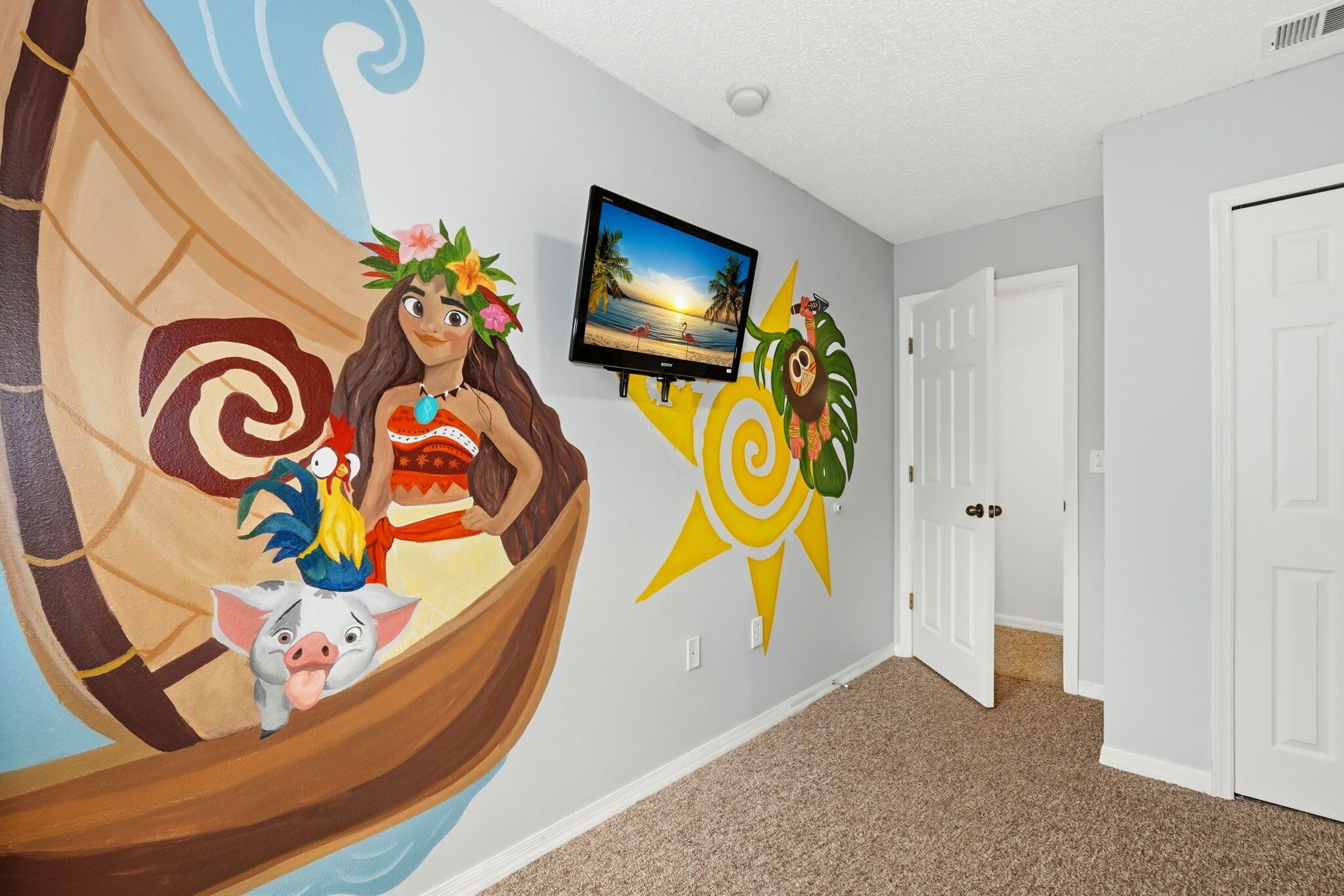 Un pasillo con un mural de un barco tradicional, un televisor montado en la pared y una puerta.