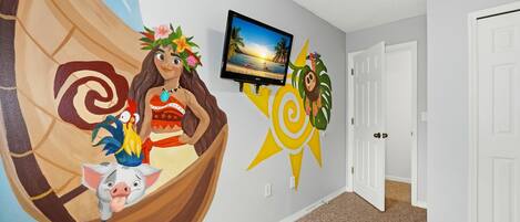 Un pasillo con un mural de un barco tradicional, un televisor montado en la pared y una puerta.