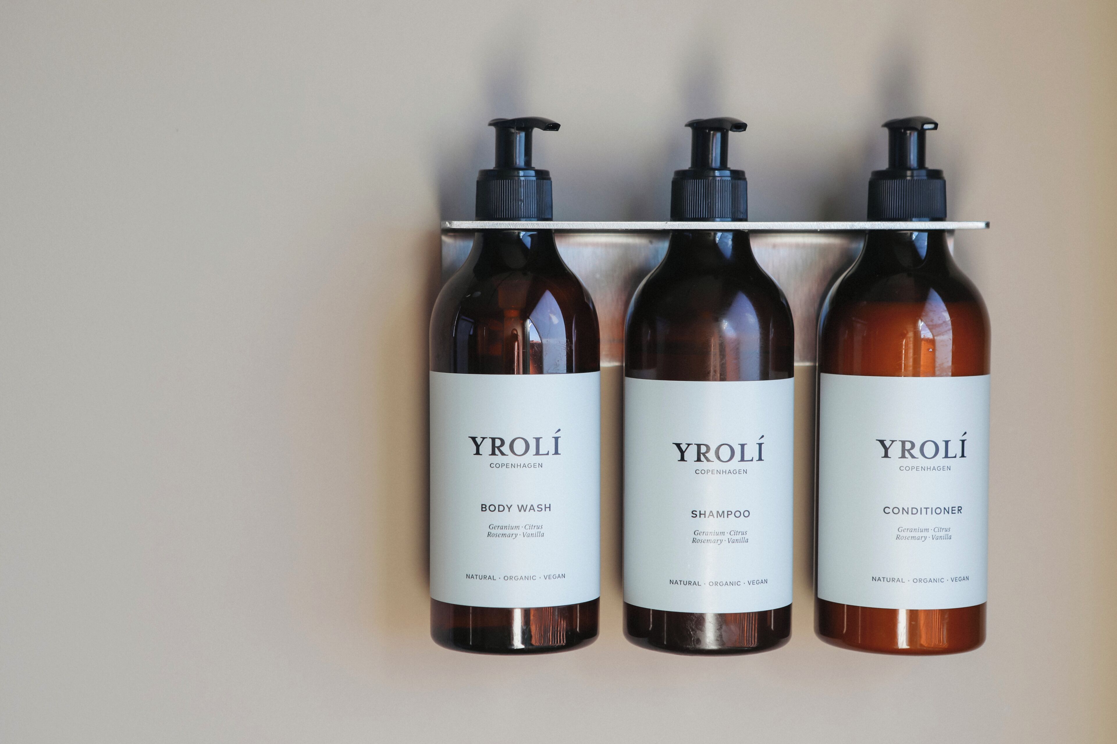 Three Yrolí Copenhagen products: body wash, shampoo, and conditioner, all labeled as natural, organic, and vegan.
