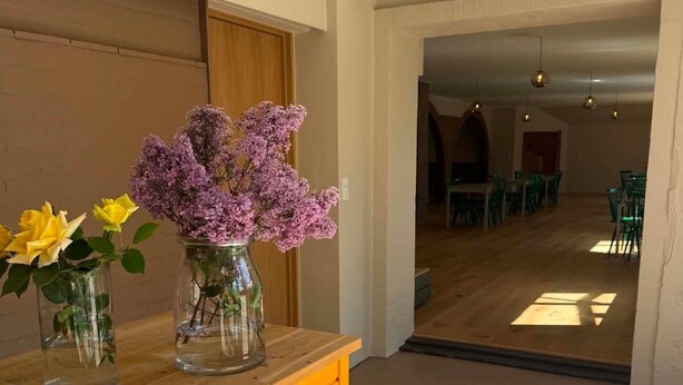 Et receptionsområde med en trædisk og vaser med blomster.