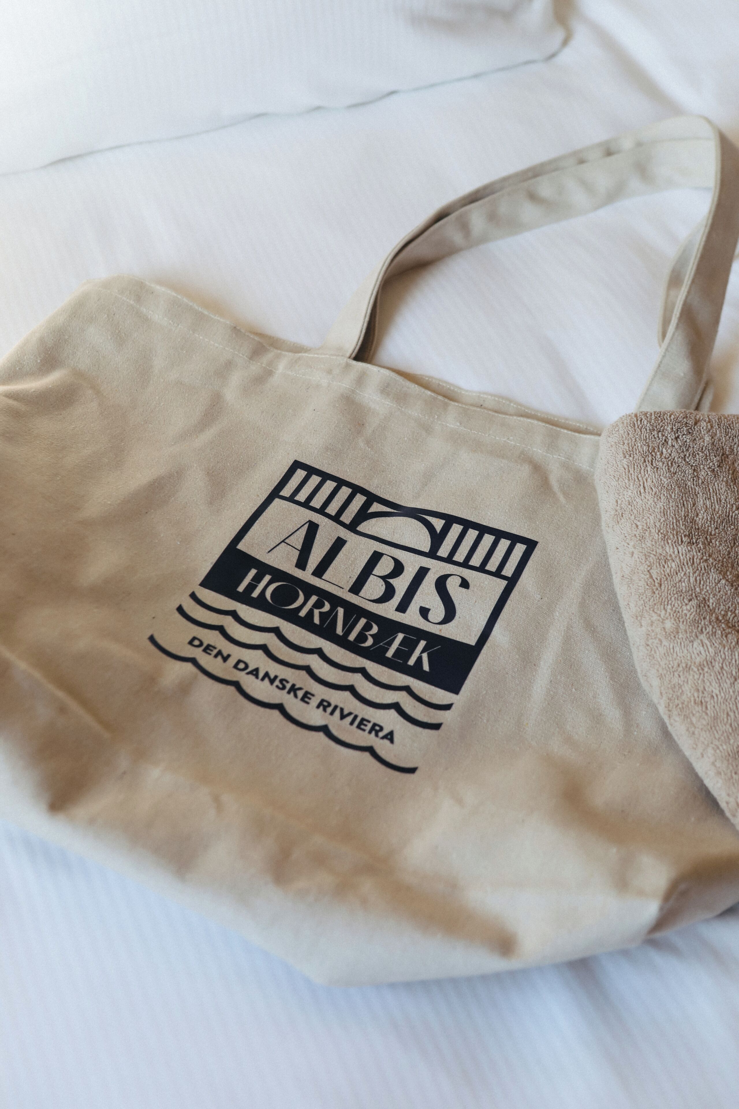 Un sac fourre-tout beige orné d’un logo et d’une inscription.
