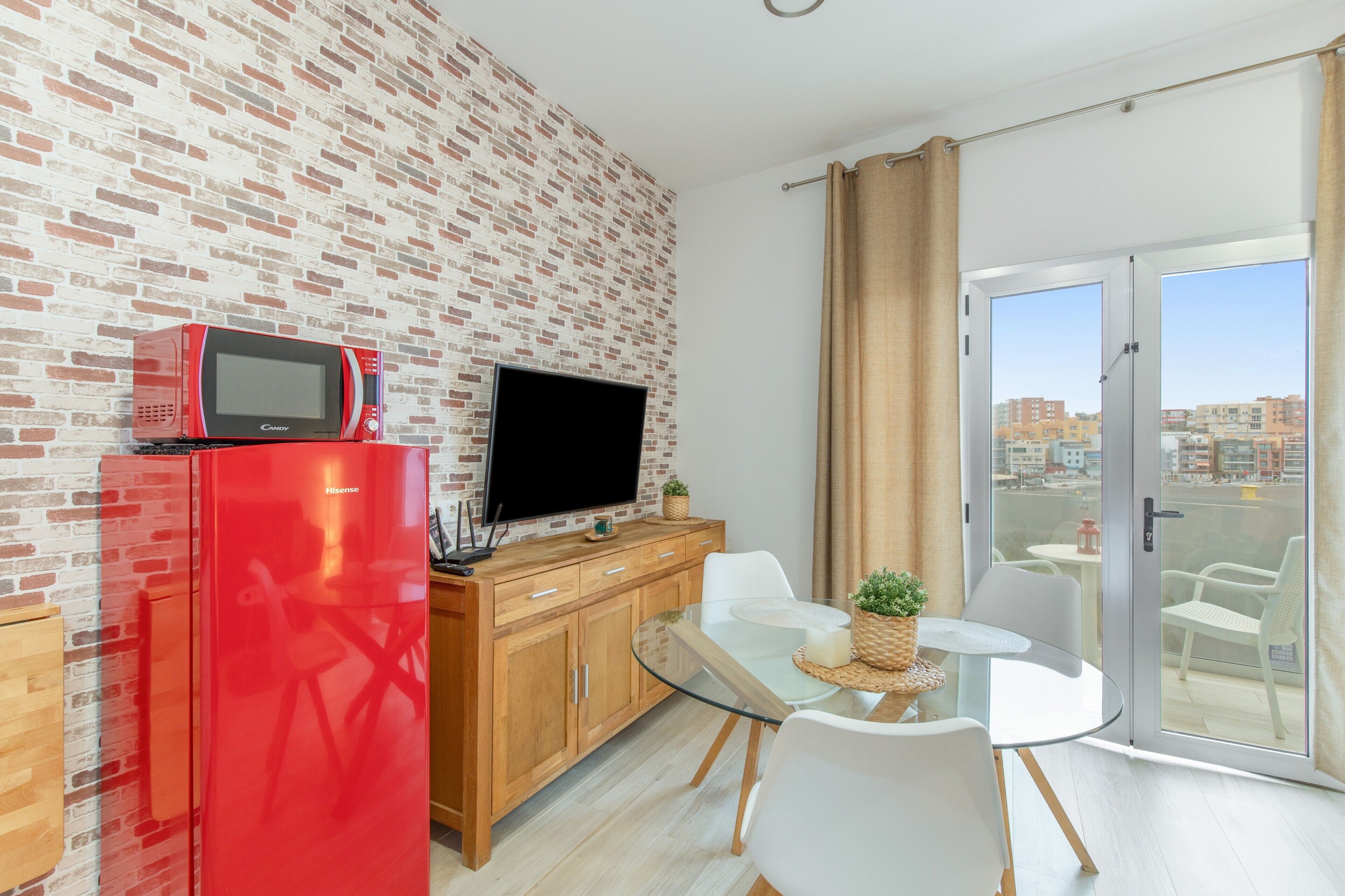 Una cocina moderna con un refrigerador rojo, un televisor de pantalla plana y un mueble de madera.