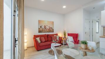 Una sala de estar moderna con un sofá rojo, una mesa de centro de vidrio y un cuadro de bicicletas.