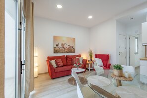Ein modernes Wohnzimmer mit einem roten Sofa, einem Glastisch und einem Gemälde von Fahrrädern.