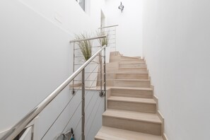 A staircase with a metal handrail and wooden steps, leading to a landing with a light fixture.