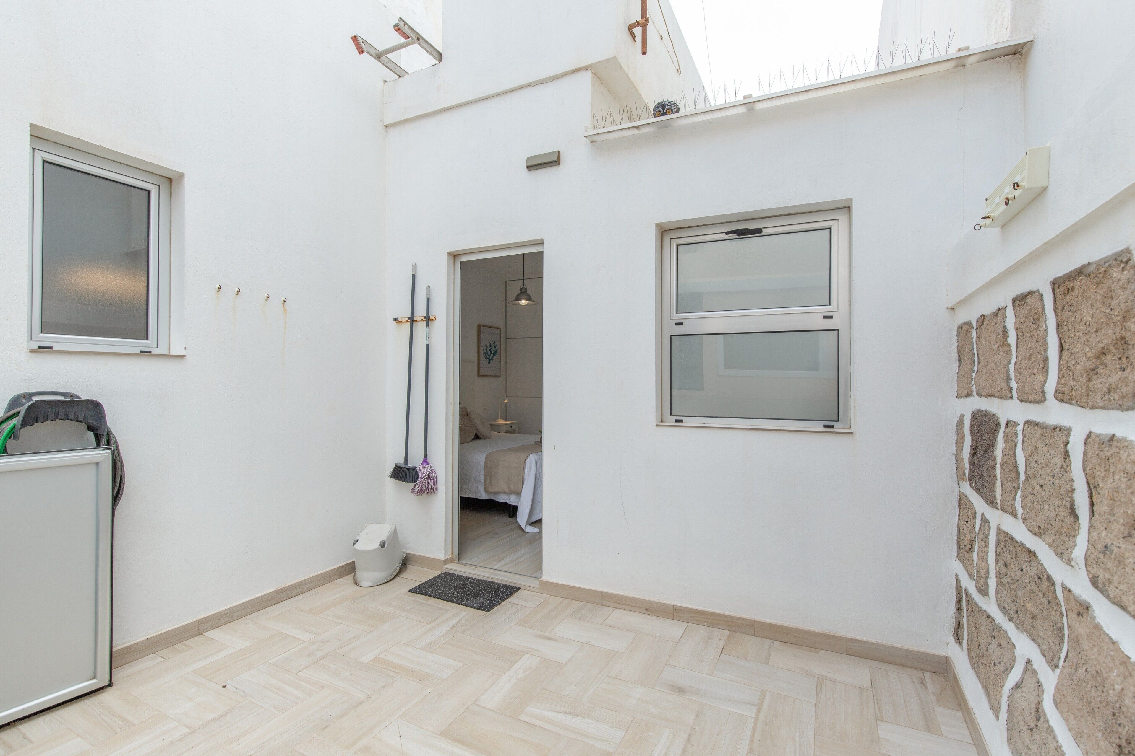 Una habitación limpia y moderna con suelo de espiga, una cama, una ventana y una puerta que da a otra habitación.