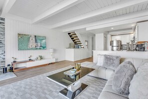 Ein modernes Wohnzimmer mit einer Couch, einem Couchtisch und einer Treppe, die in eine Küche führt.