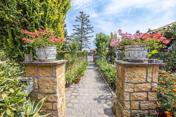 Un sendero de piedra que atraviesa un jardín con plantas y flores en macetas.