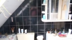 A bathroom with black tiles, a white vanity, and various toiletries. - Apartment 'Für 3 Personen 60 M²' with Shared Garden, Balcony and Wi-Fi (Harzgerode)