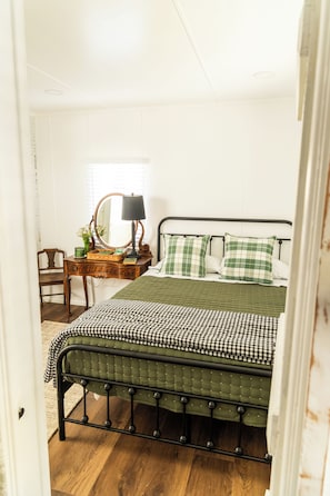 Une chambre à coucher avec un lit, une commode, un miroir et une chaise.