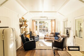 A cozy living room with a sofa, chairs, a coffee table, and a refrigerator.