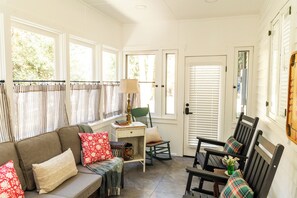 A cozy room with a sofa, chairs, a small table, and a window with curtains.