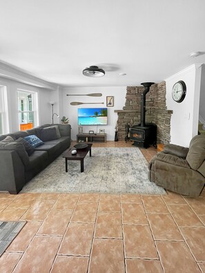 Una sala de estar con chimenea de piedra, un sofá, una mesa de centro y un televisor.
