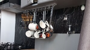 Cucina con schienale in marmo nero, lavello in acciaio inossidabile e utensili pensili.