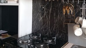 Una cucina moderna con piani di lavoro in marmo nero, piano cottura a gas ed elettrodomestici in acciaio inossidabile.