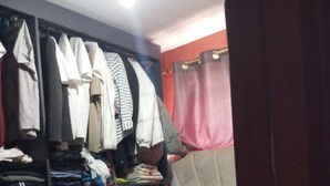Una camera da letto con un letto, un armadio e uno scaffale pieno di vestiti piegati.