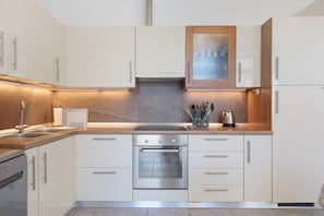 Een moderne keuken met witte kasten, roestvrijstalen apparatuur en een houten aanrecht.