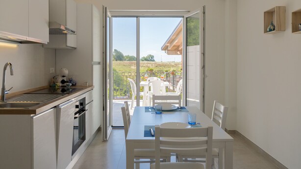 Et moderne køkken med spiseplads, en skydedør til en udendørs terrasse og udsigt over landskabet.
