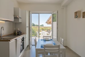 Cozinha moderna com área de refeições, porta de vidro deslizante para um pátio externo e vista para o campo.