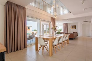 A spacious dining area with a long table, chairs, and a view of the outdoors. - Villa Principesa (Mandre)