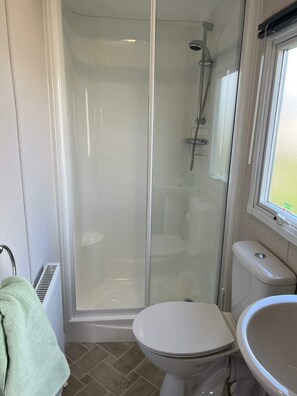 Ein Badezimmer mit einer Duschkabine, einer Toilette und einem Waschbecken.