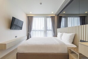 Ein modernes Hotelzimmer mit einem großen Bett, einem flachbildfernseher an der Wand und Blick auf die Stadt durch große Fenster.