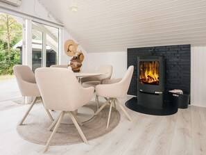 A modern interior with a round table, four chairs, a fireplace, and a view of the outdoors. - 4 Star Holiday Home in Silkeborg (Silkeborg)