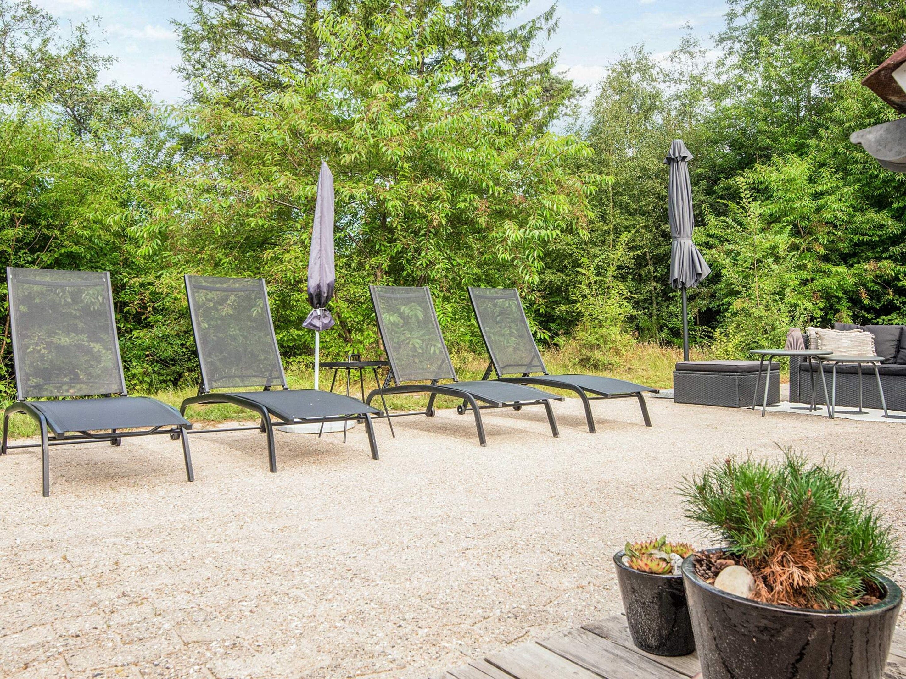A patio area with four lounge chairs, a small table, and two potted plants.