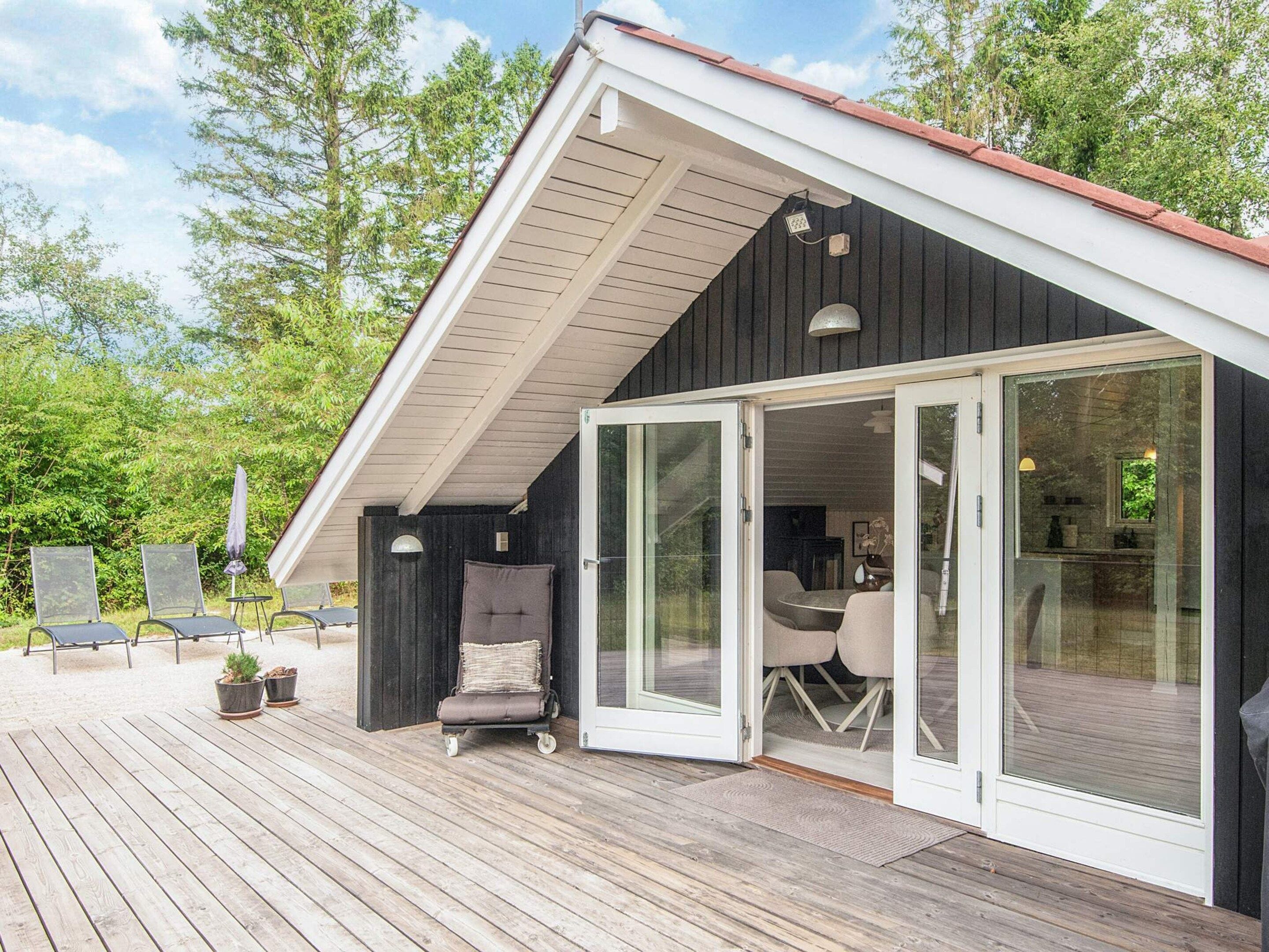 A modern house with a deck, a sliding glass door leading to an interior space, and outdoor furniture.
