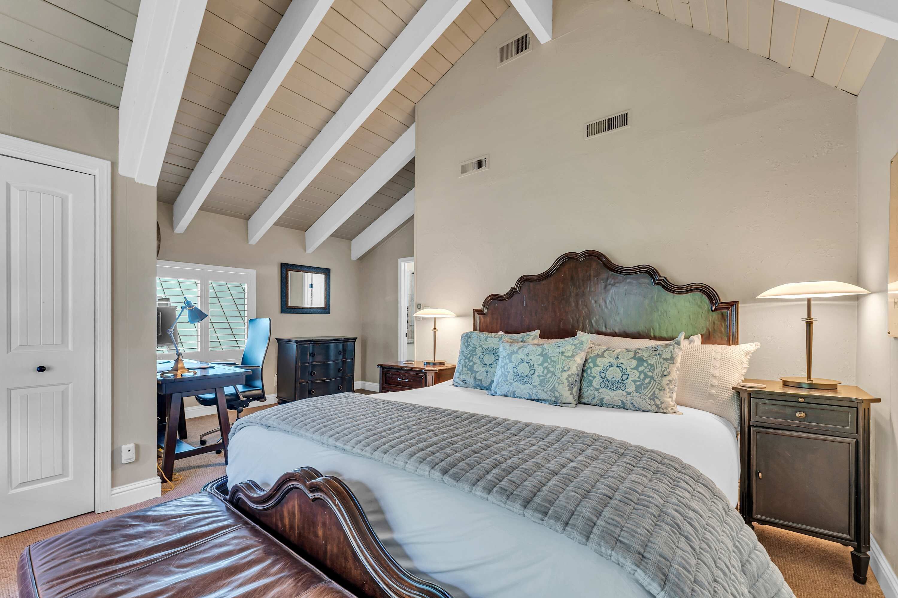 A bedroom with a large bed, a desk, and a chair.