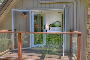 Ein Balkon mit Glastür, der zu einem Schlafzimmer mit Bett und Nachttisch führt.
