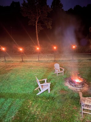 Ein grünes Freigelände mit Feuerschale und zwei Adirondack-Stühlen.