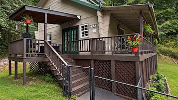 Une maison à deux étages dotée d’un porche couvert, d’un escalier et d’une terrasse délimitée par une clôture.